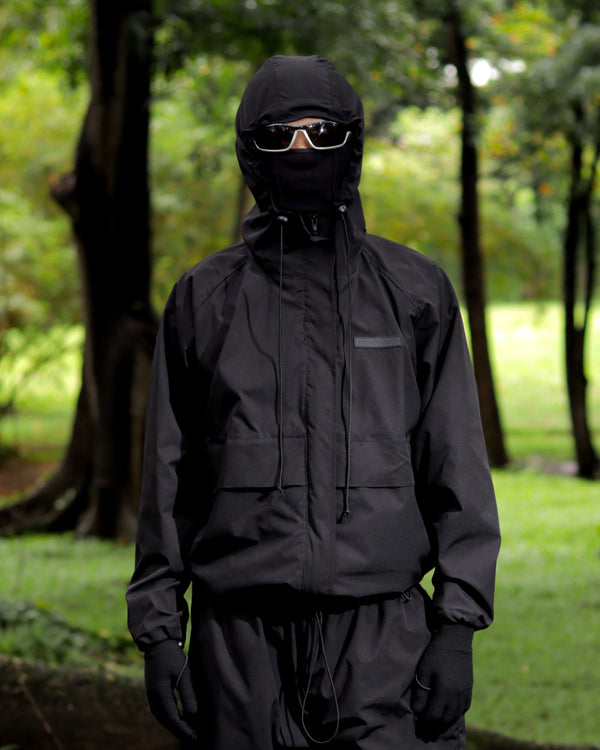 Person wearing a black raincoat and pants in a forest setting
